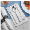 Silver cutlery placed on a white napkin, alongside a rolled set