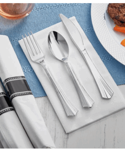 Silver cutlery placed on a white napkin, alongside a rolled set